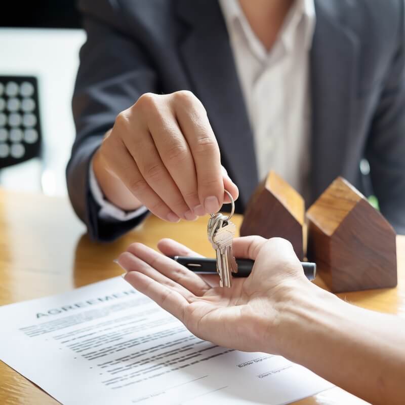 man in suit handing renter house keys where you can only see hands